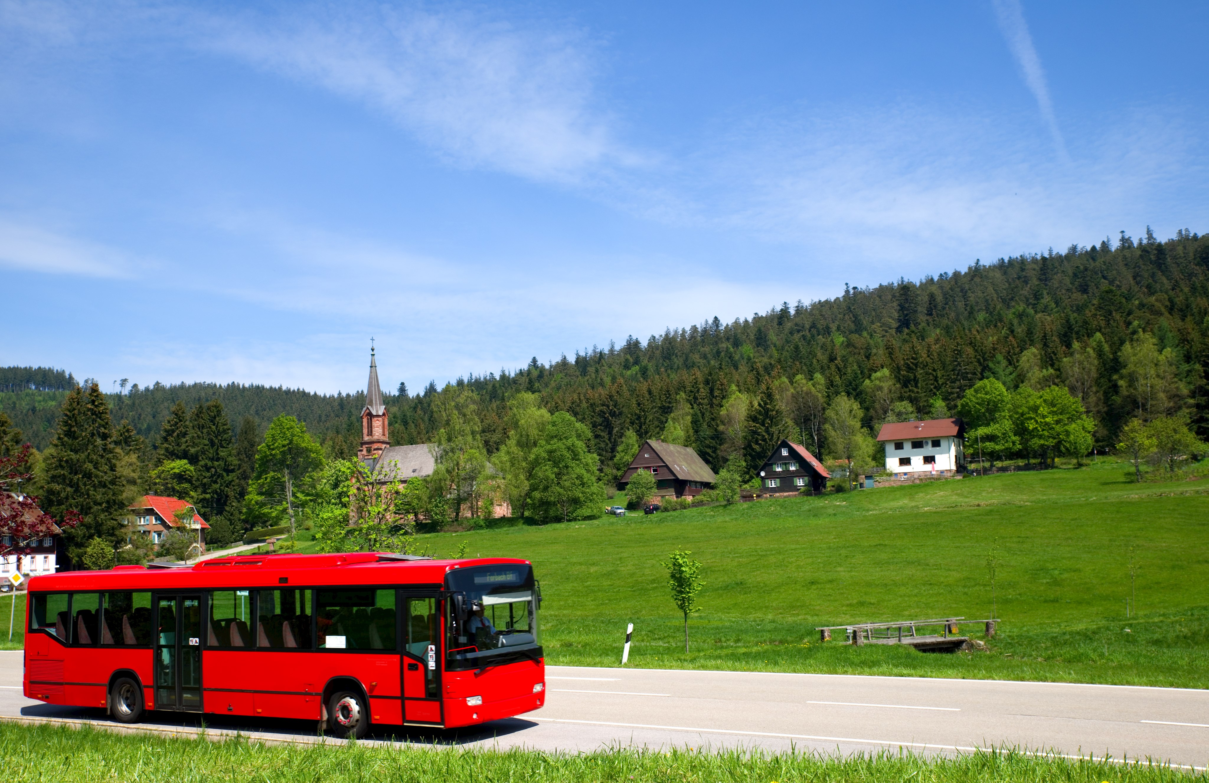 Roter Bus fährt über Landstraße